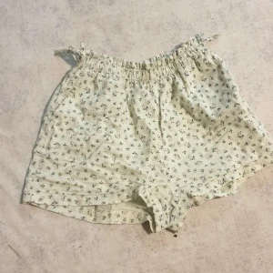 Blommiga shorts från H&M - Säljer ett par söta blommiga shorts från H&M i storlek M. De är ljusgröna med små vita och rosa blommor. Perfekta för sommardagar! Shortsen har en elastisk midja för extra komfort. 🌸 1 år gammal fast bara använda 3 gånger så typ ny
