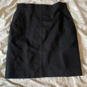 Svart kjol - Snygg svart kjol i klassisk stil. Perfekt för både vardag och festliga tillfällen. Kjolen har en enkel design utan mönster eller detaljer, vilket gör den lätt att matcha med olika toppar och accessoarer.