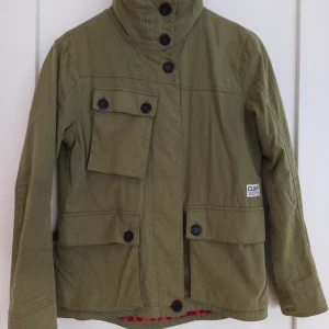 Grön jacka från CLWR Colour Wear - Tidlös grön textil jacka från CLWR Colour Wear🌟  Storlek S sitter även fint på XS. Många fina detaljer såsom fickor och knappar! Av hög kvalitet, mycket bra skick💕