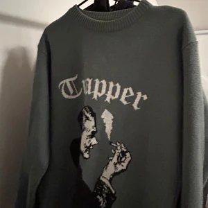 Grön tröja med tryck TRAPPER - Säljer en cool grön tröja med ett unikt tryck av en man som röker och texten 'Trapper'. Tröjan har långa ärmar och en rund halsringning. Perfekt för höst och vinter, och den ger en skön och avslappnad stil. Storlek M men är väldigt stor i storleken. Unik grön/silver/olive färg. 