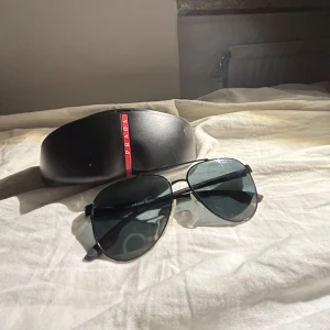 Svarta solglasögon från Prada - Säljer ett par snygga svarta solglasögon från Prada . De har en stilren design med mörka glas och en tunn metallbåge. Perfekta för både vår och sommar! Kommer med originalfodral.säljer för inte använder . Pris kan diskuteras. Tveka it skriva fråga eller annat 