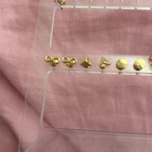 Set med guldiga örhängen - Säljer ett set med små, stilrena guldiga örhängen i olika former. Perfekta för att mixa och matcha till olika outfits. De är i nytt skick och kommer på en praktisk display. Passar både till vardag och fest! Säljer ett sett för 10kr 