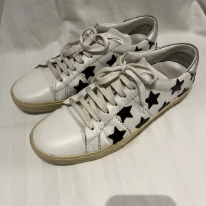 Saint Laurent star classic court - Snygga vita sneakers från Saint Laurent med svarta stjärnor med häl i silver. Väldigt bra skick men lite slitningar på sulan på olika ställen. Inget OG tillkommer. 