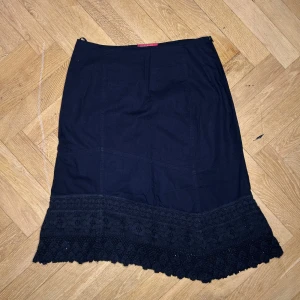 Svart kjol med spetsdetaljer - Elegant svart kjol med vackra spetsdetaljer längst ner. Kjolen har en klassisk design och är perfekt för en stilren look. Den är knälång och har en normal passform.