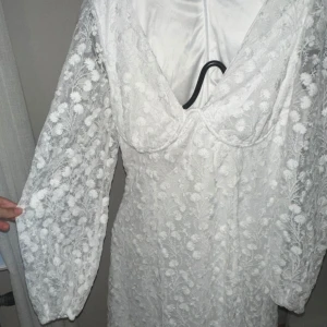 Student klänning  - Säljer en söt vit klänning med blommigt mönster och långa ärmar. Klänningen har en v-ringad design. 