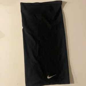Svart tubtopp från Nike - Snygg svart tubtopp från Nike med deras ikoniska logga i vitt. Perfekt för en sportig look eller som basplagg i garderoben. Enkel och stilren design som passar till mycket.
