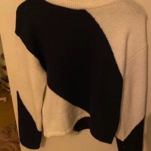 Svartvit stickad tröja - Säljer en snygg stickad tröja i svart och vitt med ett unikt geometriskt mönster. Tröjan har långa ärmar och en rund halsringning. Aldrig använd