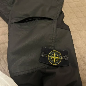 Svarta cargobyxor från Stone Island - Snygga svarta cargobyxor från Stone Island med praktiska fickor. Byxorna passar dig som har storlek S, dem passar mig inte längre. Varsamt använda äkta skinn. 