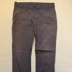 Grå chinos från Peak Performance - Snygga grå chinos från Peak Performance med en klassisk design. Byxorna har en normal passform. De har både fram- och bakfickor samt hällor för bälte. Perfekta för en stilren look.