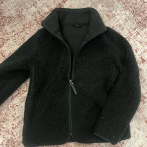 Grön fleecejacka från M&S Collection - Mysig grön fleecejacka från M&S Collection med dragkedja framtill. Perfekt för kyliga dagar med sin mjuka och varma känsla. Storlek 8 eller S.