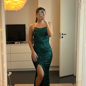 Grön glittrig klänning från Fashion Nova - Säljer en helt oanvänd klänning från Fashion Nova. Den har en tight passform med en elegant slits och smala axelband. Dragkedja finns på sidan💚