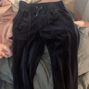 Svarta mjukisbyxor med fickor juciy mörk blå - Nästan aldrig använd Säljer ett par svarta mjukisbyxor med elastisk midja och snörning. Byxorna har praktiska fickor både fram och bak, samt en diskret logga på framsidan. Perfekta för en avslappnad stil.