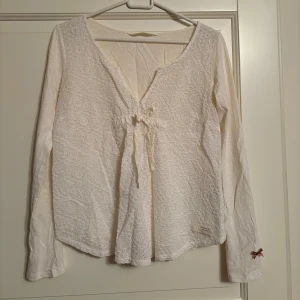 Vit OddMollyblus - Fin vit OddMollyblus med spetsdetaljer och knytband framtill. Blusen har långa ärmar och en liten rosett vid ärmslutet. Aldrig använd. Storlek 0, vilket jag tror motsvarar XS.