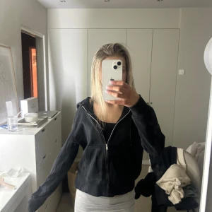 Svart hoodie med dragkedja - Säljer en svart hoodie med dragkedja och huva. Den har långa ärmar och en praktisk ficka framtill.  I storlek xxs 