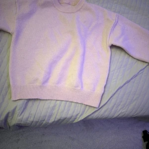 Ljusrosa stickad tröja - Mysig ljusrosa stickad tröja med rund halsringning och ribbade muddar vid ärmslut och nederkant. Perfekt för kyliga dagar och ger en stilren look.