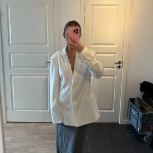 Vit kavaj - Snygg vit kavaj med klassisk design och knappar framtill. Perfekt för en stilren look. Kavajen har långa ärmar och en normal passform.