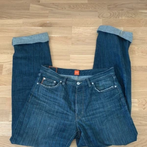 Jeans från Hugo Boss - Snygga jeans från Hugo Boss i en mörkblå nyans. De har en klassisk femficksdesign och är tillverkade i 100% bomull. Byxorna har en normal passform och är w35 l36 i storlek. Perfekta för en stilren look. (Inga flaws)