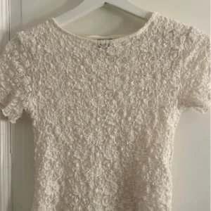 Vit spetsblus - Säljer en elegant vit spetsblus med korta ärmar. Blusen har ett vackert blommönster och en rund halsringning. Perfekt för en stilren look. superfin blus från Gina dom inte sälja längre ❤️