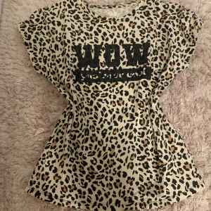 Leopardmönstrad t-shirt från Firefly - Säljer en cool leopardmönstrad t-shirt från Firefly med texten 'WOW' på framsidan. Tillverkad av 100% återvunnen polyester. Perfekt för dig som vill sticka ut med ett djärvt mönster. Och väldigt bekväm att ha på sig! 🐆
