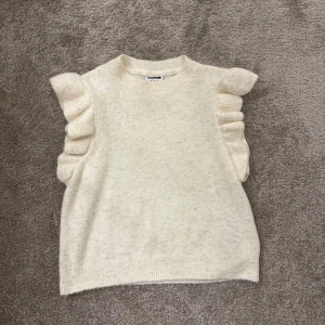 Vit stickad topp med volangdetaljer - Säljer en söt vit stickad topp med volangdetaljer på axlarna. Perfekt nu till våren och sommaren💕