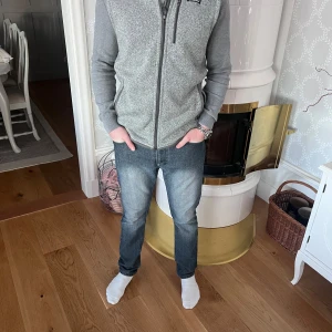 Grå pantagionia väst - Säljer en grå fleecejacka med dragkedja och långärmade ärmar. Perfekt för kyliga dagar och har en bekväm passform. Jackan har en stilren design med en liten logga på bröstet.