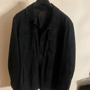 Blå mockajacka - Snygg blå mockajacka med knappar och klassisk krage. Jackan har praktiska fickor och en stilren design som passar perfekt för höst och vår. Blå och mocka kommer definitivt blir trendigt till våren och sommaren