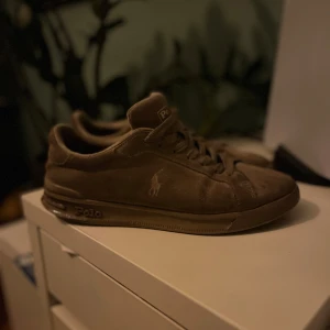 Beigea sneakers från Polo Ralph Lauren - Snygga beiga sneakers från Polo Ralph Lauren med klassisk snörning och diskret logga på sidan. Perfekta för en stilren vardagslook.