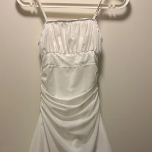 Vit klänning med spetsdetaljer - Kort klänning, ej genomskinlig och bra material, aldrig använd då den ej hann komma till tillfället.