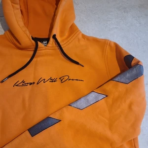 Hoodie med tryck - Orange hoodie från Kings Will Dream med text både fram och bak. Lite sliten, nypris ca 400.