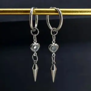 Snygga silverfärgade örhängen med en liten hjärtformad detalj och en spetsig hängande del. Handgjorda örhängen●Följ :@ekjewelryofficial🤲 ● 💎Material- 100% rostfritt stål ●Örhängeskrokar -rostfritt stål och kristall. Nickel fri. Längd -5,5cm. Vattentåliga, ändrar inte färgen! 