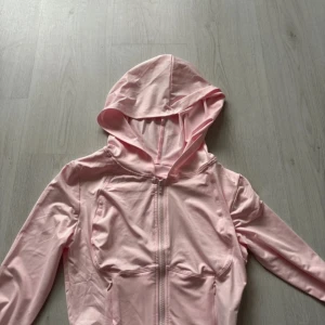 Rosa träningstopp - Säljer en ljusrosa hoodie med dragkedja och huva. Den har långa ärmar och är tillverkad i ett mjukt material, perfekt för träning eller vardags.🤍
