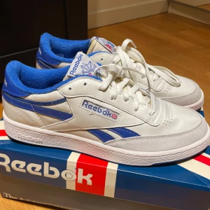 Reebok Club C Revenge Vintage - Snygga vita Reebok sneakers med blå detaljer och snörning. Skorna har använts en gång inomhus och har inga alls defekter. Nypris: 1300 kr. Strl: 45 1/2
