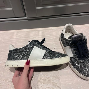 Glittriga sneakers från Valentino - Säljer mina älskade valentino skor, vänster skon har alla taggar kvar och är i jätte bra skick, höger skon har tyvärr tappat tre taggar och tråden till sulan har gått upp (se sista bilden) de har varit så hela tiden jag har haft dom men ingen som syns när man går eller som påverkar när man går, det går att laga för runt 300kr men jag har inte haft tid med det🤗 sjukt bra pris!! Storlek 36 men de är stora i storleken, passar mig som har 37 i vanliga fall❣️