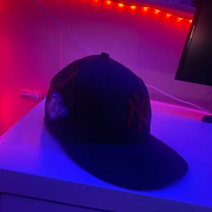 Mörk blå keps från New Era - Snygg mörk blå keps från New Era med broderad logotyp framtill. Perfekt för att komplettera din stil med en sportig touch. Kepsen har en klassisk design och är en del av 59FIFTY-serien.