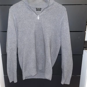 Grå tröja från Massimo Dutti - Snygg grå tröja från Massimo Dutti med dragkedja vid halsen. Perfekt för kyligare dagar med sin mjuka och bekväma passform. 
