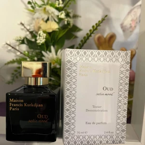 Maison Francis Kurkdjian Oud Satin Mood Eau de Parfum - Elegant och lyxig parfym med en djup och sensuell doft av oud. Flaskan är svart med en gyllene kork och text i guld. Förpackningen är stilren med ett geometriskt mönster.