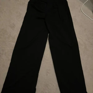 Svarta kostymbyxor - Snygga svarta kostymbyxor. Perfekta för en stilren look. Byxorna har knappar och hällor för bälte.