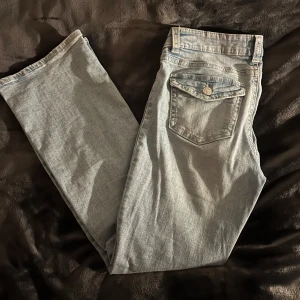 Blå bootcut jeans - Snygga blå bootcut jeans med klassisk femficksdesign och knappgylf. Perfekta för en avslappnad stil.