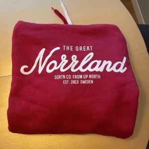Röd hoodie från SQRTN - Säljer en snygg röd hoodie från SQRTN med texten 'The Great Norrland' tryckt i vitt på framsidan. Perfekt för att hålla sig varm och stilren under kyliga dagar. Tröjan är använd 1 gång i min ägo så är näst in till ny.