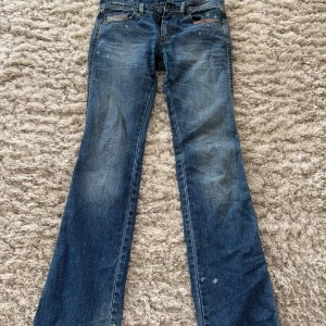Blå bootcut jeans - Säljer ett par klassiska blå bootcut jeans med slitna detaljer. Säljer pga blivit för små. Mått: innerbenslängd: 82cm hela ben: 98cm midjemått: 79 cm 
