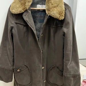 Marlboro classics jacka - Snygg brun brun kappa från Marlboro classics med mjuk päls på kragen. Jackan har knappar framtill och praktiska fickor med knappdetaljer. 