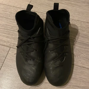 Svarta fotbollsskor från Nike - Snygga svarta fotbollsskor från Nike med snörning och en diskret vit Nike-logga på sidan. Perfekta för fotbollsplanen med en tight passform som ger bra kontroll.