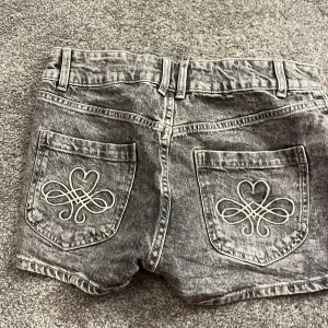 Grå jeansshorts från Lindex - Snygga grå jeansshorts från Lindex med coolt mönster på bakfickorna. Shortsen har två knappar och dragkedja fram, samt fem fickor totalt. Super snygga, inga fläckar men jag har använt dem ett par gånger. Perfekta till sommaren!❤️