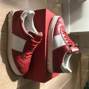 Valentino Flycrew - Snygga röda Flycrews med vita detaljer från Valentino. Skorna har snörning och en klassisk design som passar perfekt för en stilren look.