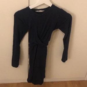 Mörkblå klänning med lång ärm - Snygg mörkblå klänning med lång ärm och rund hals. Perfekt för kyligare dagar och kan stylas upp eller ner beroende på tillfälle.