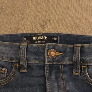 Blå jeans från Hollister - Snygga blå jeans från Hollister i modellen mid-rise boot. De har en klassisk femficksdesign och en knappgylf med dragkedja. Perfekta för en avslappnad stil.