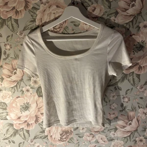 Vit ribbad topp - Säljer en stilren vit ribbad topp med korta ärmar och rund halsringning. Perfekt för en avslappnad look.