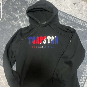 Svart hoodie från Trapstar - Säljer en svart hoodie från Trapstar. Använd några gånger. Den är i bra skick. Perfekt för skola,jobb eller ha den på vardagar 