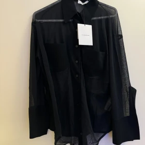 Svart skjorta från Victoria Beckham - Snygg och stilren svart skjorta från Victoria Beckham i lätt bomull. Skjortan har långa ärmar och knappar framtill, perfekt för en elegant look. Nypris 5500 kr. Pris kan diskuteras. Oanvänd & lappen sitter kvar 