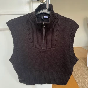 Svart stickad väst med dragkedja - Snygg svart stickad väst med hög krage och dragkedja framtill från H&M. En aning croppad. Perfekt för lager-på-lager stil. Ribbad kant vid ärmhål och nederkant. Fint skick🖤